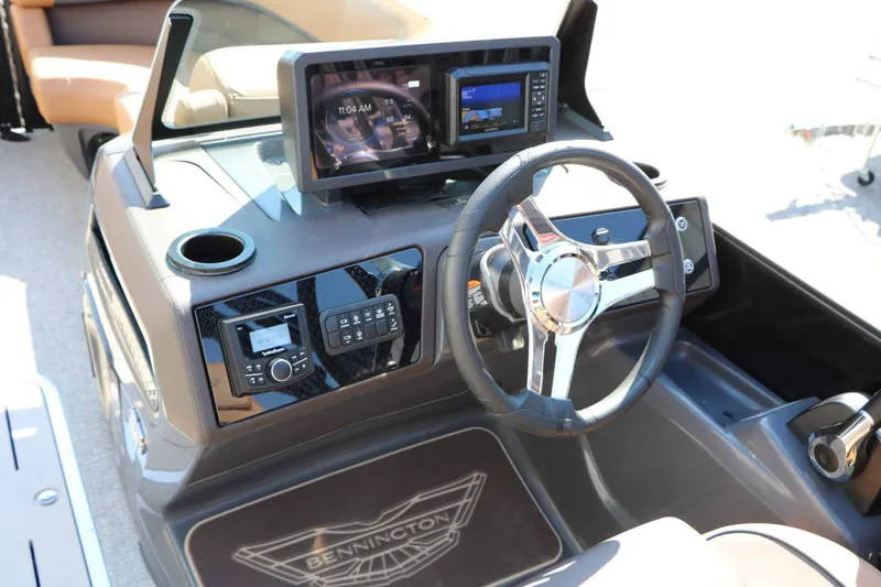 Slide: The Image of The image shows the helm of a Bennington 23 MFB Tri Toon with modern instruments and a sleek steering wheel. - 48