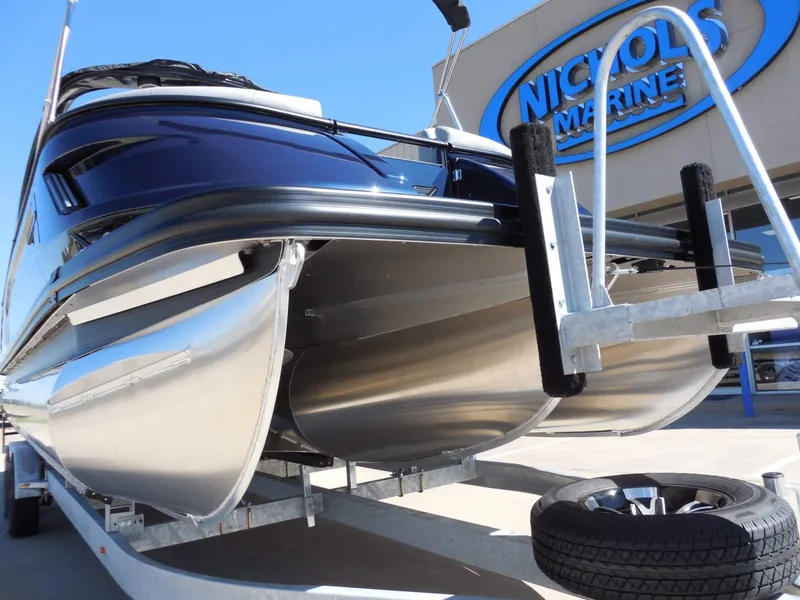 Slide: The Image of A Bennington 25 QXFBA pontoon boat on a trailer in front of a marine store. - 14