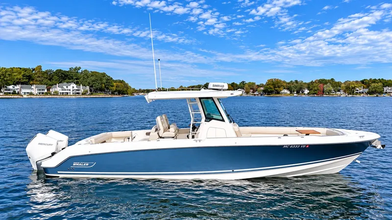 Slide: The Image of Boston Whaler 330 Outrage 2024 on calm water with blue hull and white deck. - 33
