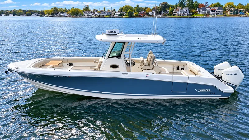 Slide: The Image of A 2024 Boston Whaler 330 Outrage on calm water with a blue hull and twin Mercury engines. - 32
