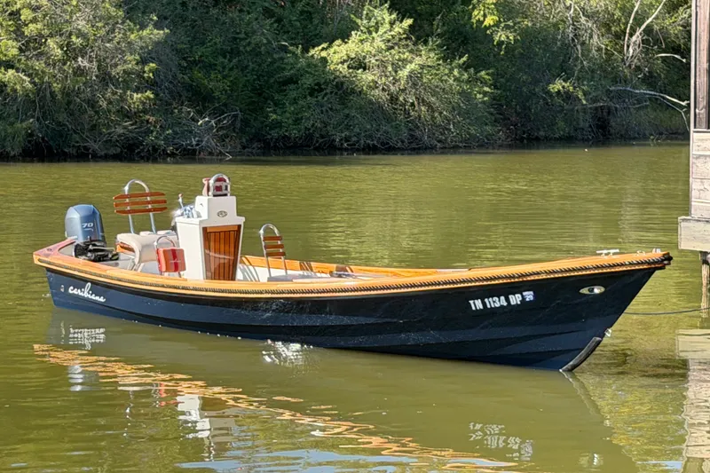 The Image of 2019 Caribiana Maracas 23 Skiff on calm water near a wooded shoreline. - 1