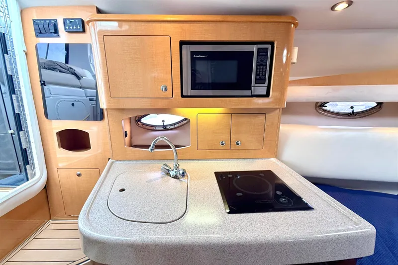 Slide: The Image of 2009 Four Winns 278 Vista boat interior with kitchenette, featuring sink, stove, and microwave. - 19
