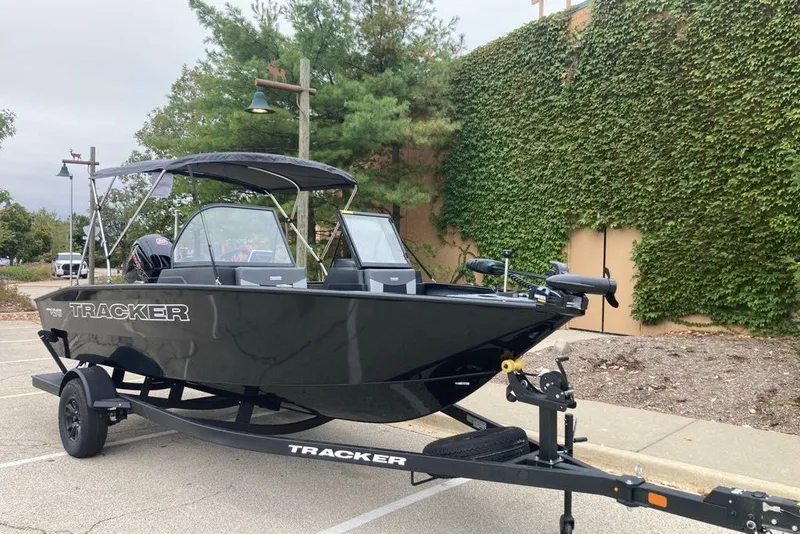 Slide: The Image of 2027 Tracker Targa V-18 Combo boat on trailer, parked outdoors with greenery background. - 55