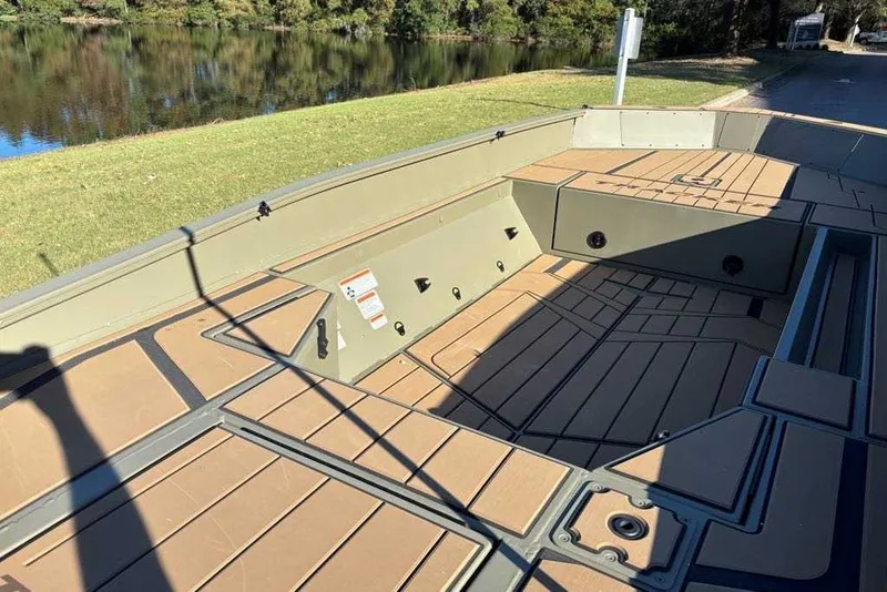 Slide: The Image of 2027 Tracker Grizzly 1553 Timber boat interior with wood-patterned flooring by a lake. - 51