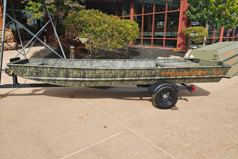 The Image of 2027 Tracker Grizzly 15 Jon boat on trailer, parked outdoors near a building. - 0
