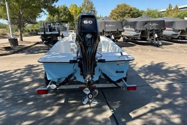 Slide: The Image of 2027 Mako Pro Skiff 15 CC boat with 60 HP engine, parked outdoors. - 15