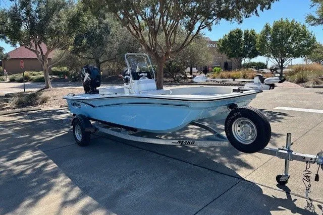 Slide: The Image of 2027 Mako Pro Skiff 15 CC boat on trailer in outdoor setting. - 2