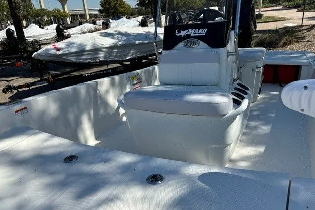 Slide: The Image of 2027 Mako Pro Skiff 15 CC boat interior with seating and console, parked outdoors. - 10