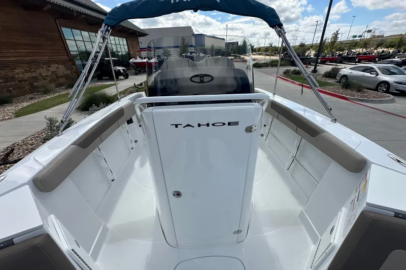 Slide: The Image of 2027 Tahoe 2150 CC boat interior with seating and console, parked outdoors. - 22