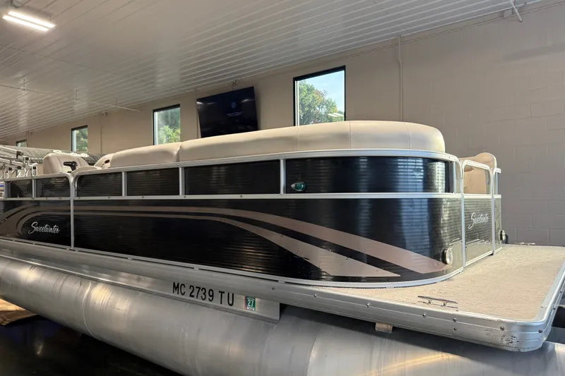 Slide: The Image of 2014 Sweetwater 2286 pontoon boat in indoor showroom, featuring sleek black and silver design. - 15