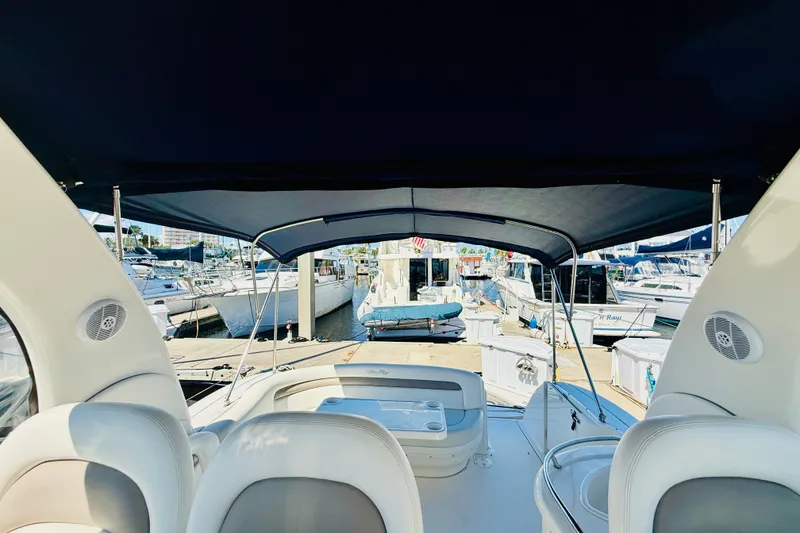 Slide: The Image of 2005 Sea Ray 340 Sundancer interior view at marina, showcasing seating and canopy. - 22
