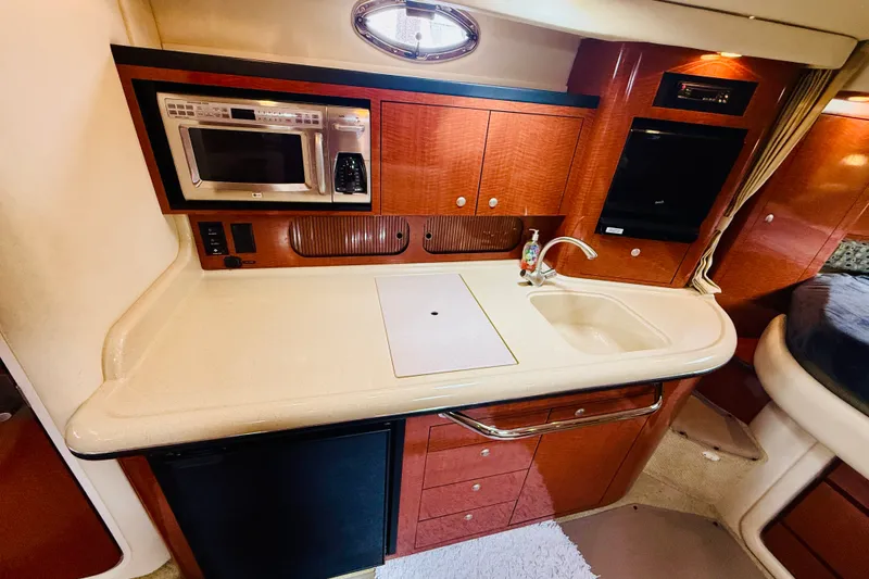 Slide: The Image of 2005 Sea Ray 340 Sundancer galley with microwave, sink, and wood cabinetry. - 59