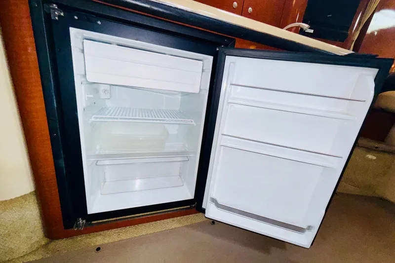 Slide: The Image of Open refrigerator inside 2005 Sea Ray 340 Sundancer yacht, showcasing interior storage space. - 56