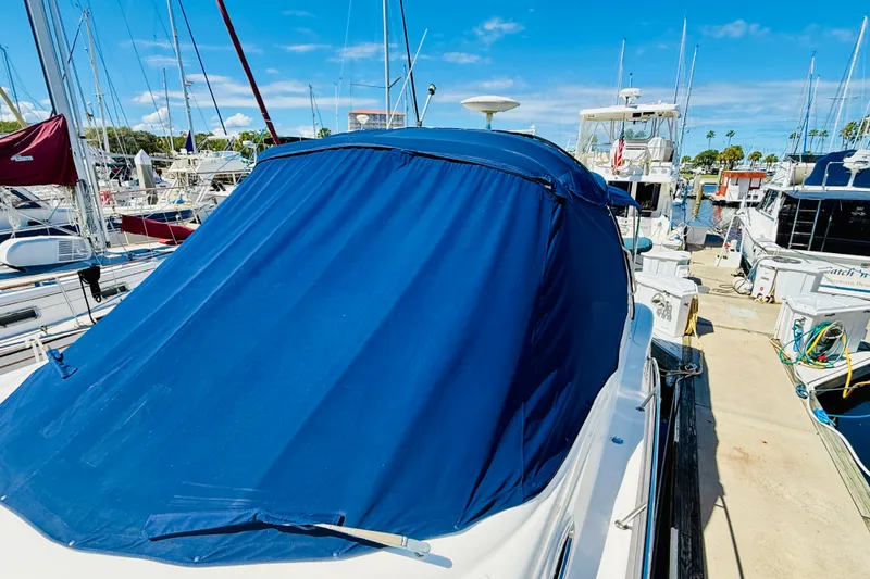Slide: The Image of 2005 Sea Ray 340 Sundancer with blue cover docked at marina under clear sky. - 34