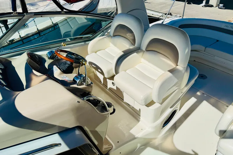 Slide: The Image of 2005 Sea Ray 340 Sundancer cockpit with dual white leather seats and steering wheel. - 31