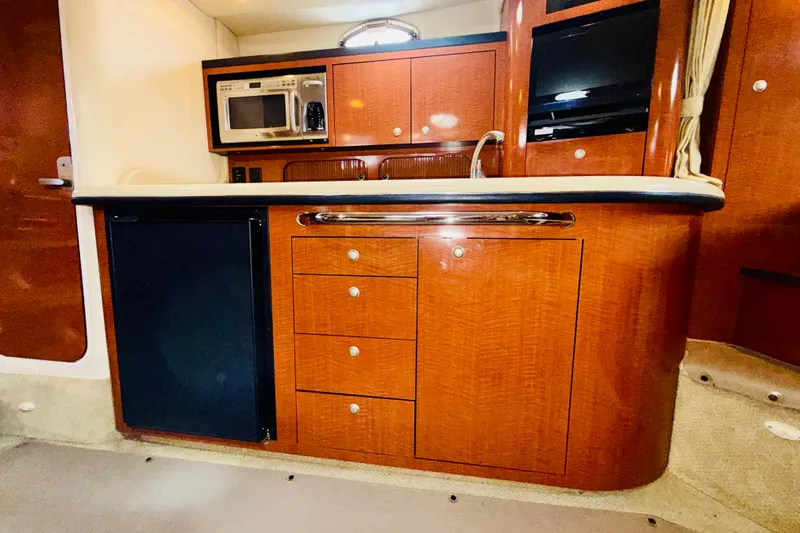 Slide: The Image of 2005 Sea Ray 340 Sundancer interior kitchen with wood cabinetry, microwave, and sink. - 57