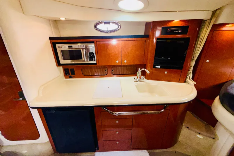 Slide: The Image of 2005 Sea Ray 340 Sundancer galley with microwave, sink, and wood cabinetry. - 58
