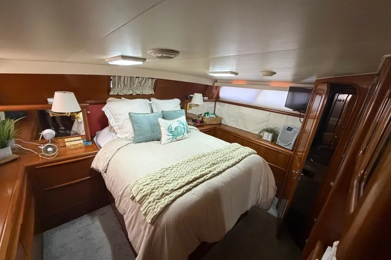 Slide: The Image of Cozy bedroom interior of 1990 Viking 44 Motor Yacht with elegant wood finish and plush bedding. - 36