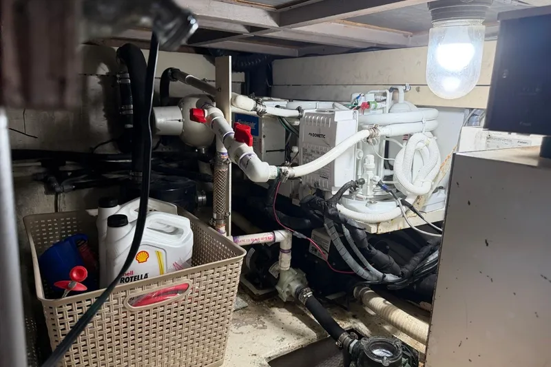 Slide: The Image of Engine room of a 1990 Viking 44 Motor Yacht with mechanical components and storage basket. - 48