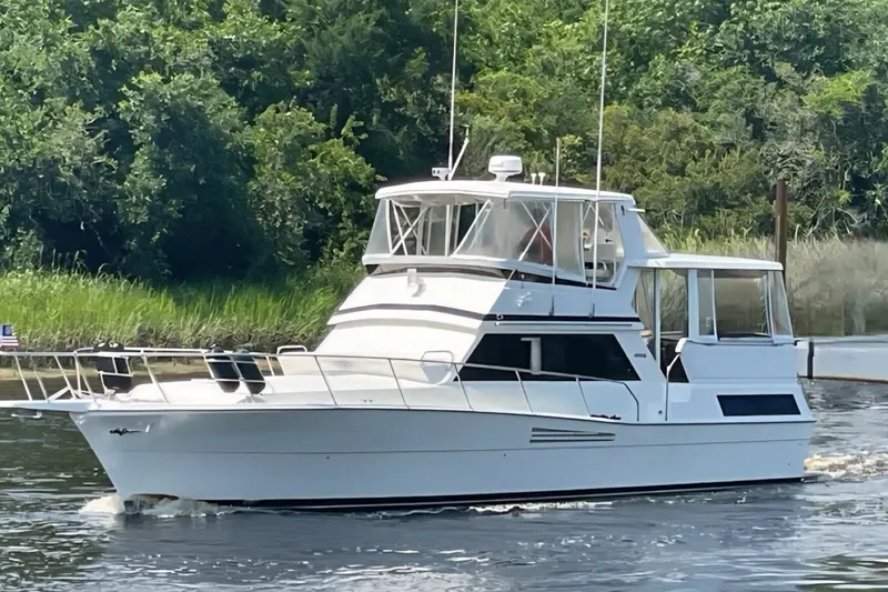 The Image of 1990 Viking 44 Motor Yacht cruising on a serene waterway with lush greenery. - 0