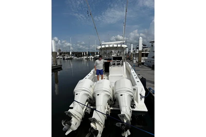 Slide: The Image of A 2006 Contender 36 Fisharound docked at a marina. Three outboard engines are mounted at the stern. - 4