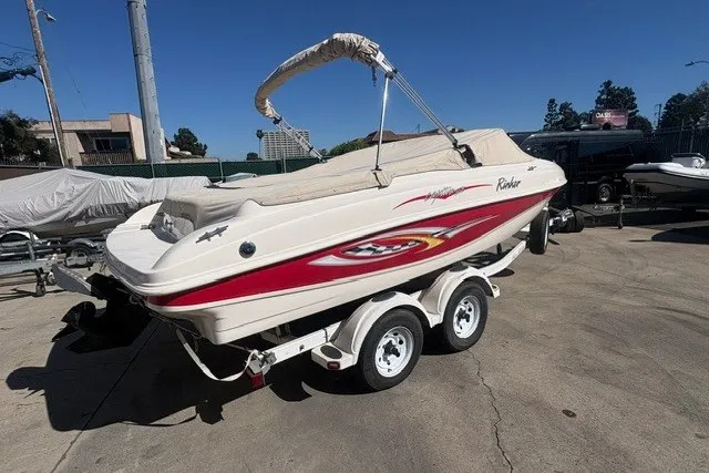 Slide: The Image of 2002 Rinker 212 Captiva Bowrider on trailer, parked outdoors under clear sky. - 4