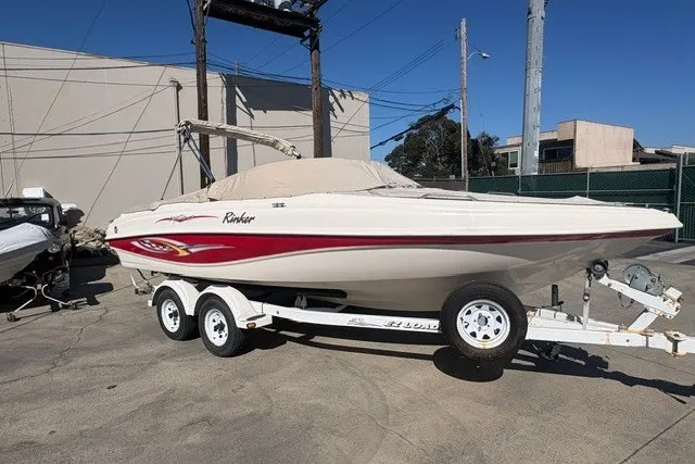 Slide: The Image of 2002 Rinker 212 Captiva Bowrider on trailer, parked outdoors, covered and ready for transport. - 1