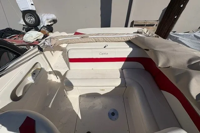Slide: The Image of 2002 Rinker 212 Captiva Bowrider interior with red and white seating, partially covered. - 12