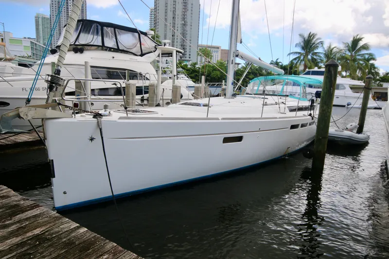 The Image of 2012 Jeanneau Sun Odyssey 509 sailboat docked in a marina with palm trees. - 0