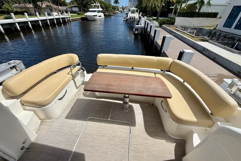 Slide: The Image of 2019 Carver C37 Coupe yacht with spacious outdoor seating and wooden table by the water. - 19