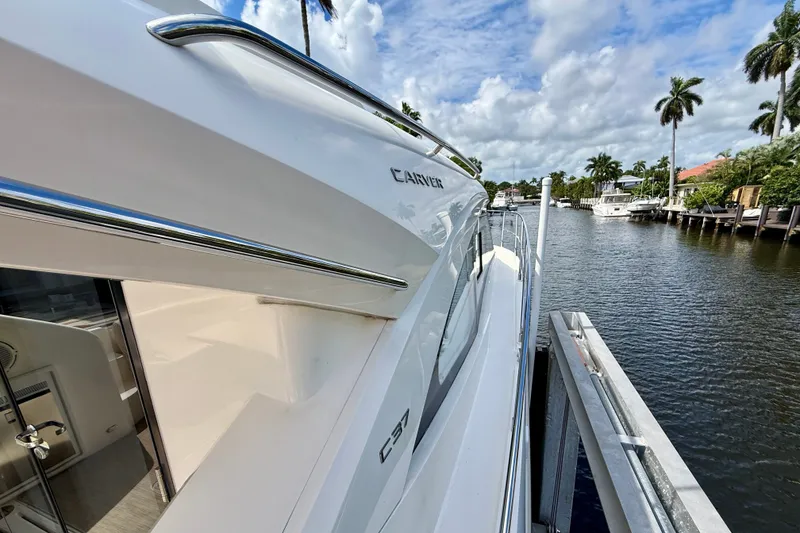 Slide: The Image of 2019 Carver C37 Coupe yacht docked by a scenic waterfront with palm trees. - 22