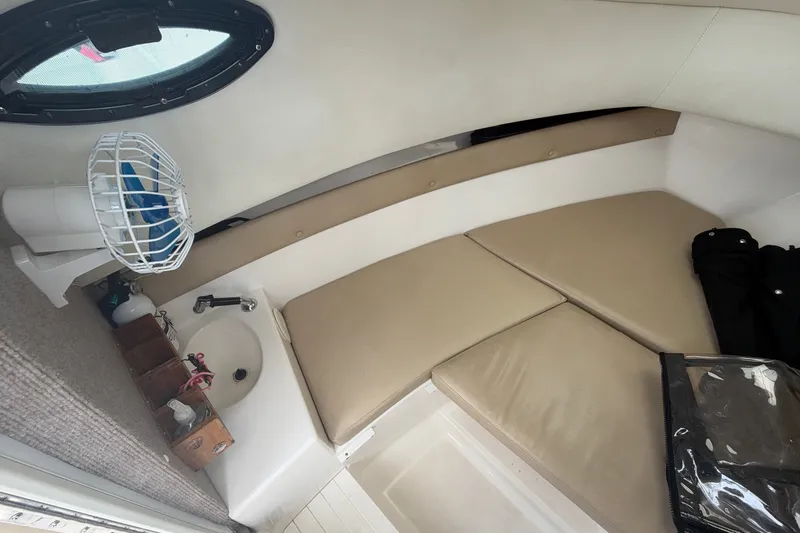 Slide: The Image of Interior cabin of 2006 Century 2200 Walk-Around boat with beige cushions and small sink. - 9