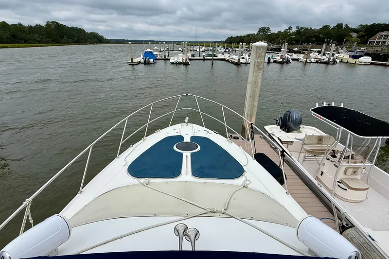 Slide: The Image of 2003 Regal Commodore 3880 yacht docked at a marina, surrounded by calm waters and boats. - 21