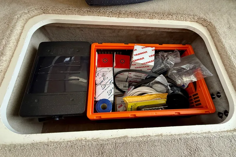 Slide: The Image of An open storage compartment with an orange box filled with tools and spare parts. - 49