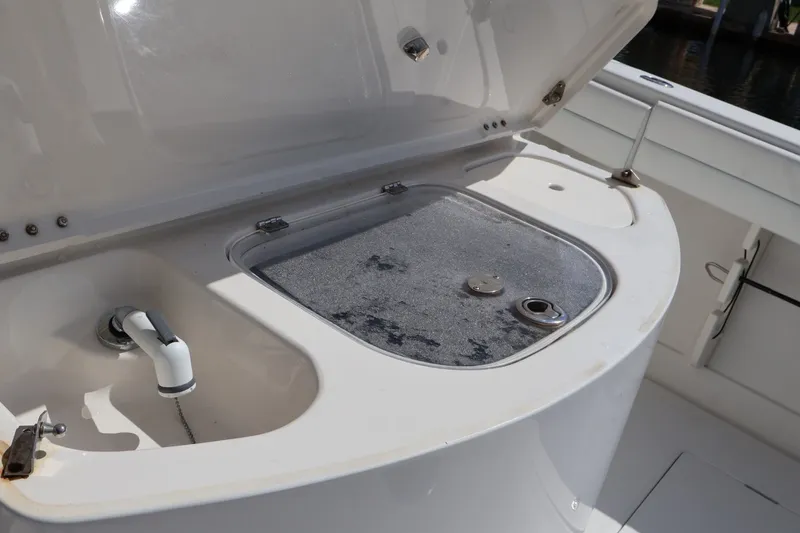 Slide: The Image of Open storage compartment on a 2006 Jupiter 38 HFS boat, featuring a faucet and hatch. - 29