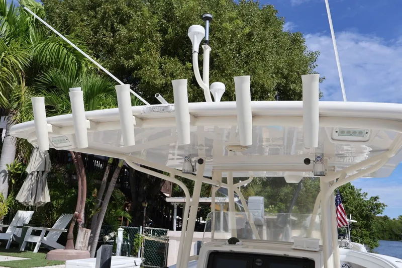 Slide: The Image of 2006 Jupiter 38 HFS boat with rod holders and canopy, docked near lush greenery. - 28