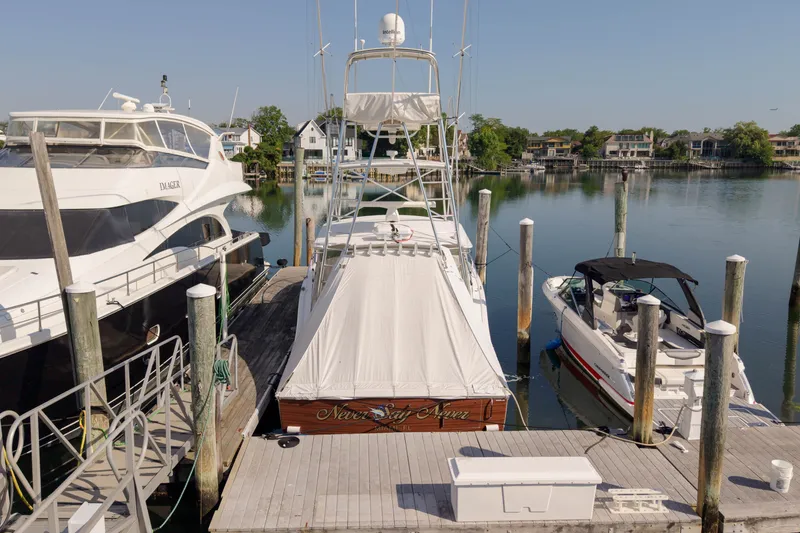 Slide: The Image of 2009 Cabo 40 Express yacht docked between boats in a serene marina setting. - 61