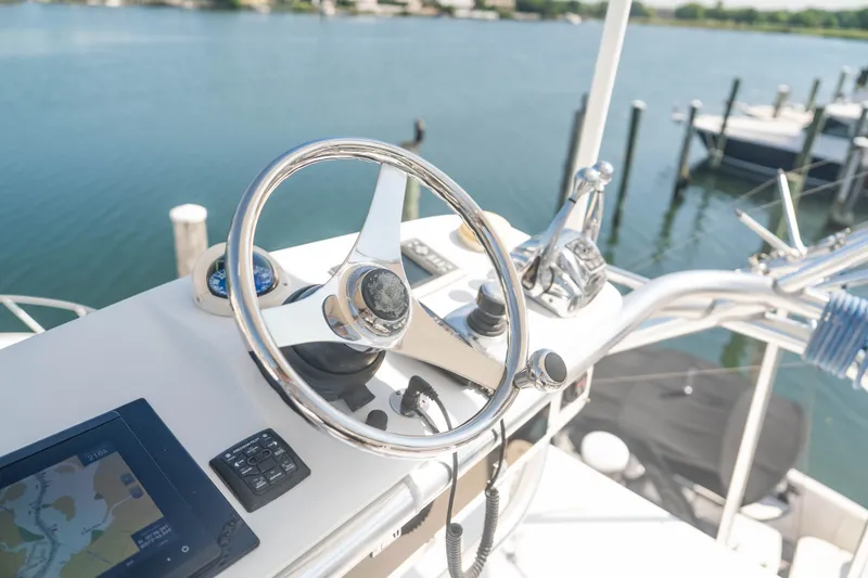 Slide: The Image of Steering wheel and controls of a 2009 Cabo 40 Express boat, overlooking a serene marina. - 23