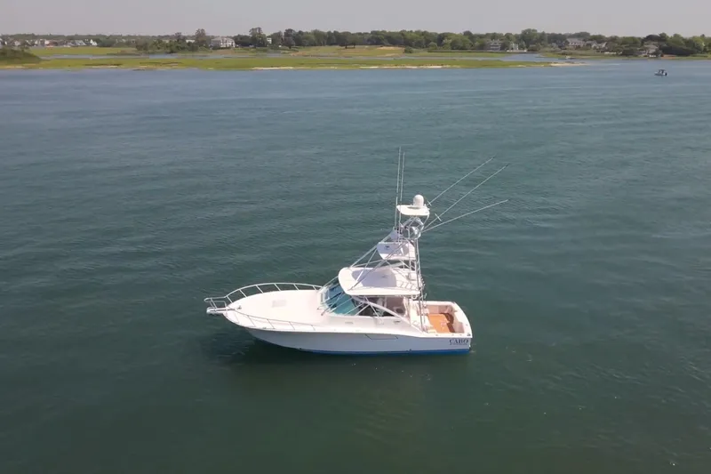 Slide: The Image of 2009 Cabo 40 Express yacht cruising on calm waters near a scenic shoreline. - 0