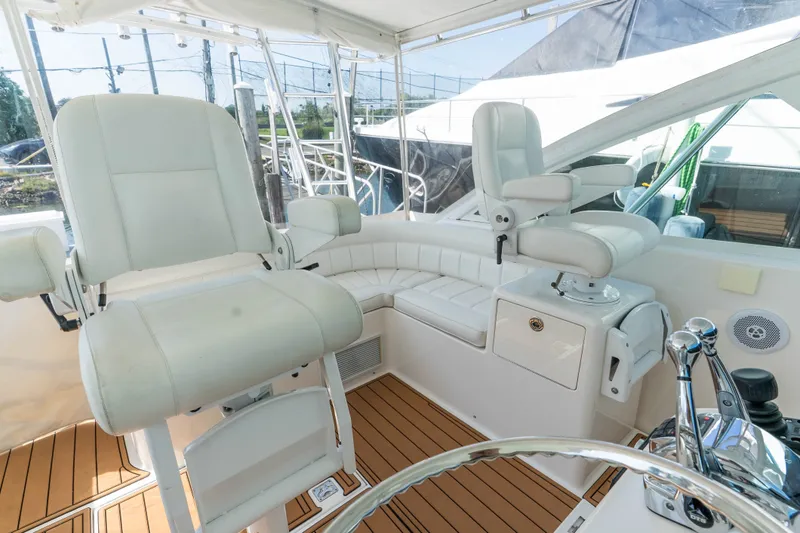 Slide: The Image of 2009 Cabo 40 Express yacht helm with white seating and wooden flooring. - 13