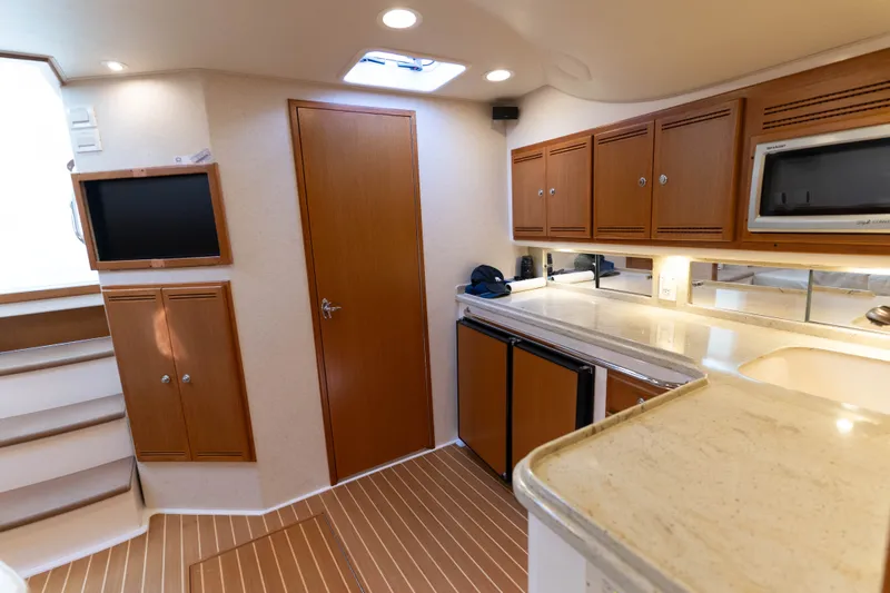Slide: The Image of 2009 Cabo 40 Express yacht interior with wooden cabinets, kitchenette, and modern amenities. - 35
