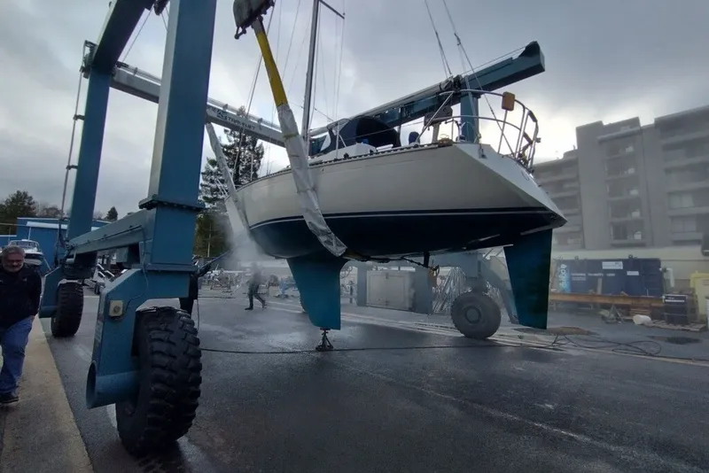 Slide: The Image of 1989 C&C 30 MKII sailboat being lifted by a crane in a marina setting. - 89