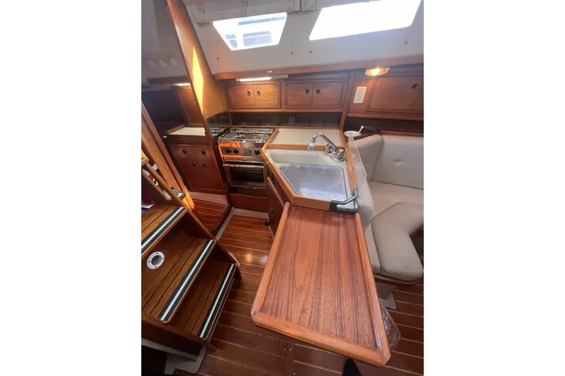 Slide: The Image of Interior of 1989 C&C 30 MKII sailboat, featuring wooden cabinetry and compact kitchen area. - 68