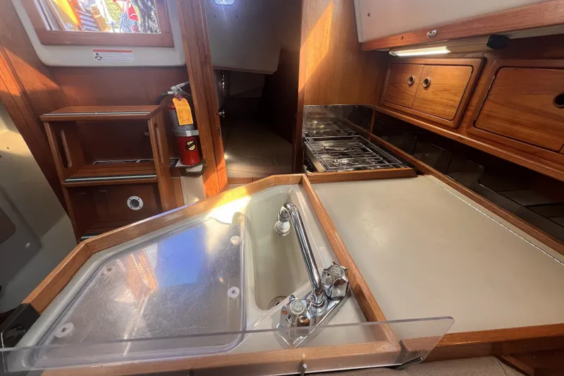 Slide: The Image of Interior of 1989 C&C 30 MKII sailboat, featuring a compact kitchen with stove and sink. - 63