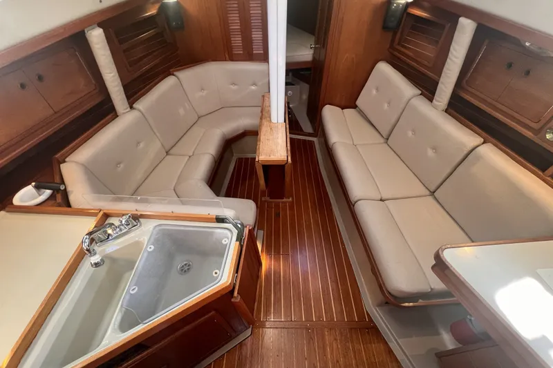 Slide: The Image of 1989 C&C 30 MKII yacht interior with beige seating, wooden flooring, and compact kitchen sink. - 72