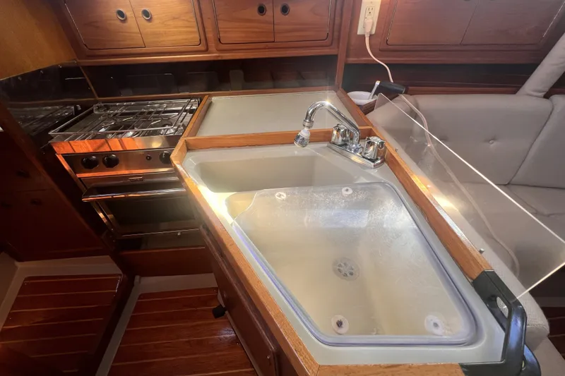 Slide: The Image of 1989 C&C 30 MKII yacht kitchen with stove, sink, and wooden cabinetry. - 62