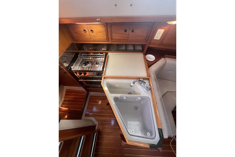Slide: The Image of Interior of 1989 C&C 30 MKII sailboat galley with stove, sink, and wooden cabinetry. - 64