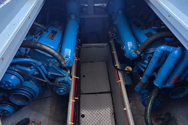 Slide: The Image of Engine room of a 1989 Silverton 34 Convertible boat, featuring twin blue engines. - 36