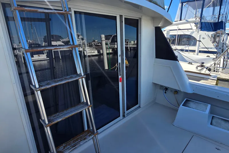 Slide: The Image of 1989 Silverton 34 Convertible yacht with ladder and sliding glass doors at marina. - 16