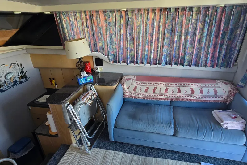 Slide: The Image of Interior of 1989 Silverton 34 Convertible with blue sofa, patterned curtains, and compact kitchenette. - 18